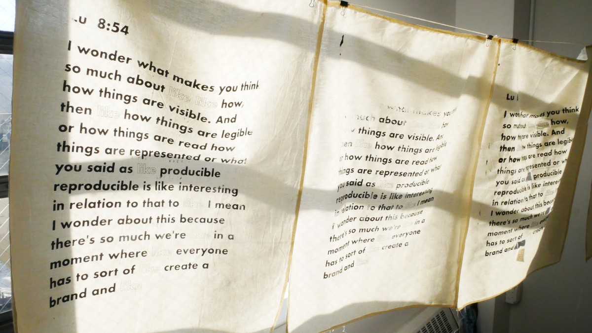 Fabric banners of a silkscreened interview transcript hanging by a window